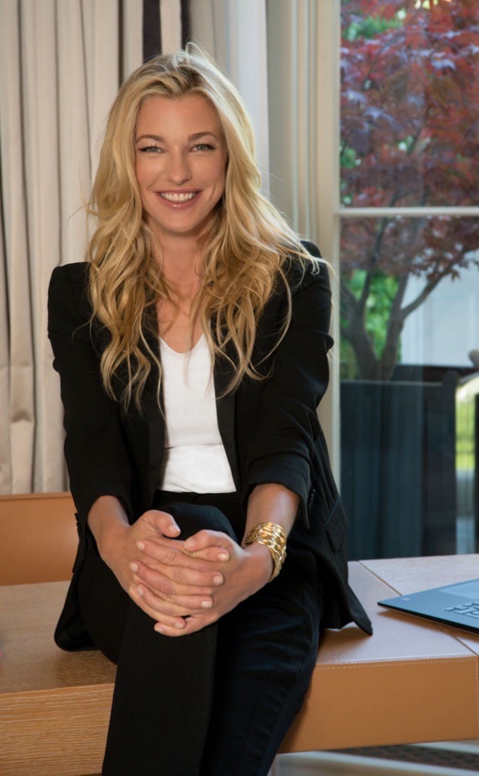 Nicole Junkerman lächelt warm, an einen hellen Schreibtisch am Fenster gelehnt.